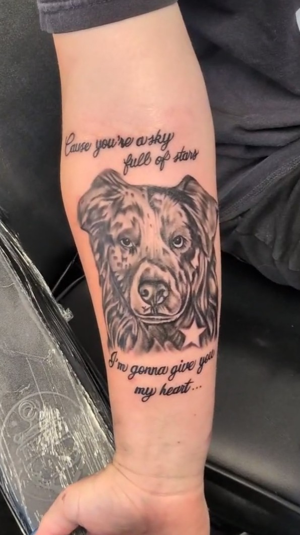 Pet portrait tattoo with lyrics on a forearm
